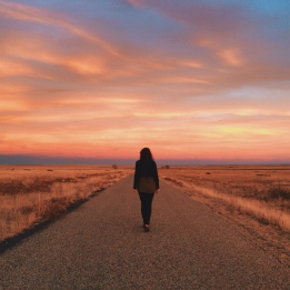 عکس راه رفتن دختر تنها در جاده هنگام غروب آفتاب