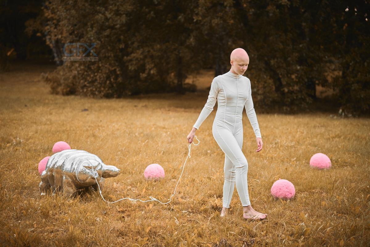 Portrait of young hairless girl with alopecia in white cloth walking tardigrade toy in fall park