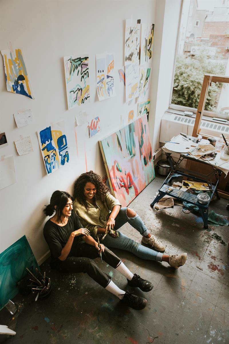 دو دوست هنرمند Sitting on the Floor در Art Studio شاد